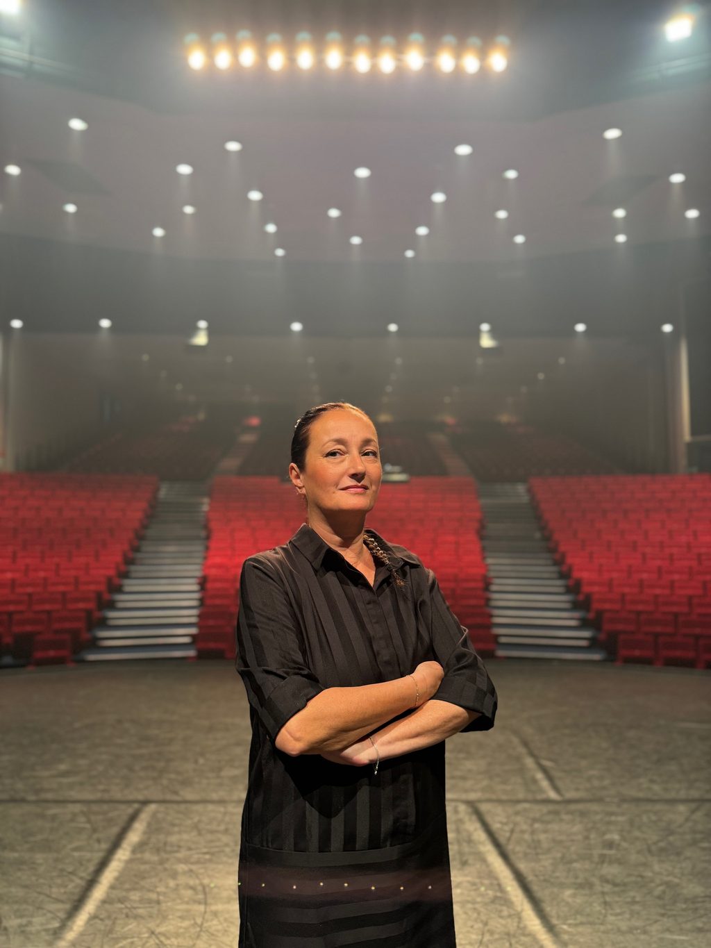 Alexandra Gérard on the stage of the Théâtre Capellia, the empty auditorium behind her