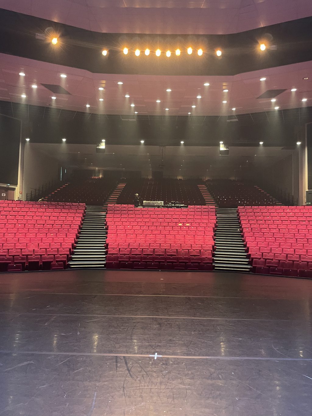 The auditorium of the Théâtre Capellia seen from the stage: banks of red seats