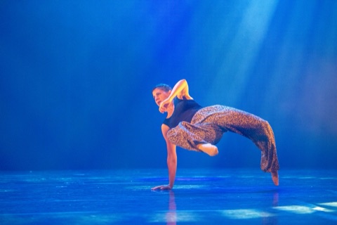 Danseuse en appui sur une main, jambes levées, éclairage bleu